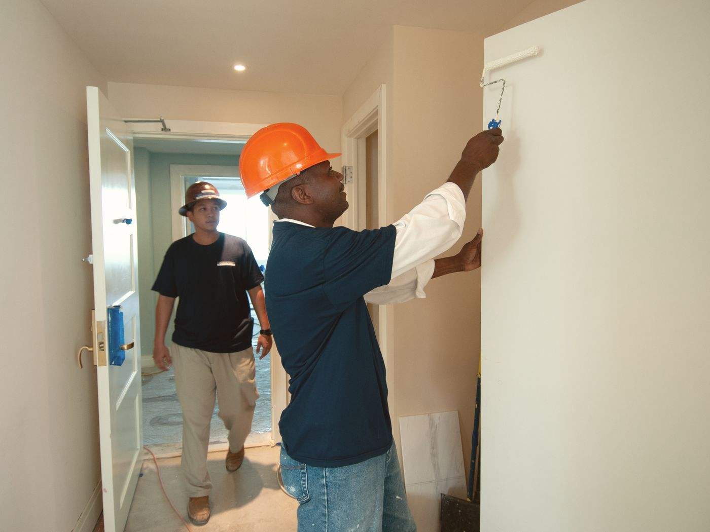 Painters rolling paint onto an interior wall, the kind of interior painting we do in Boston