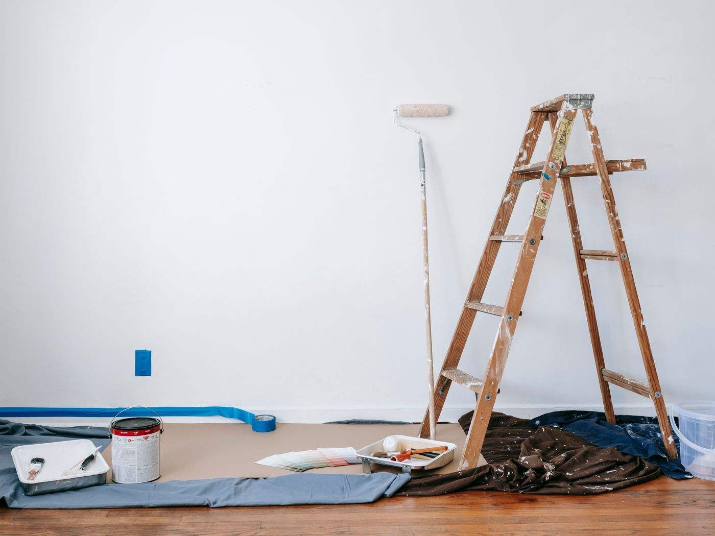 Room prepared for interior painting with a ladder, drop cloth and paint supplies