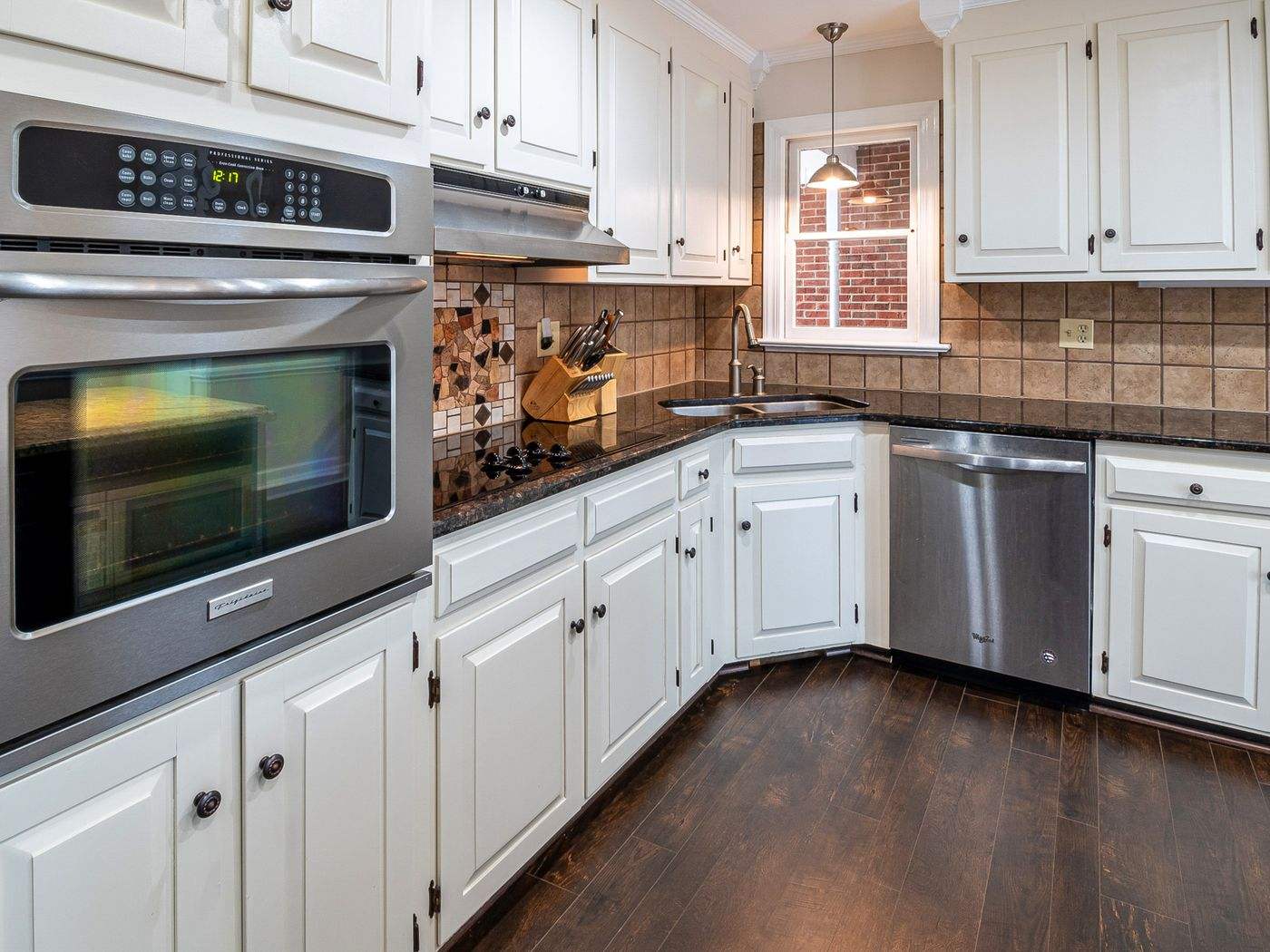 Cabinet painting Newton MA: Spacious kitchen with white cabinets, stainless steel appliances and wood floors